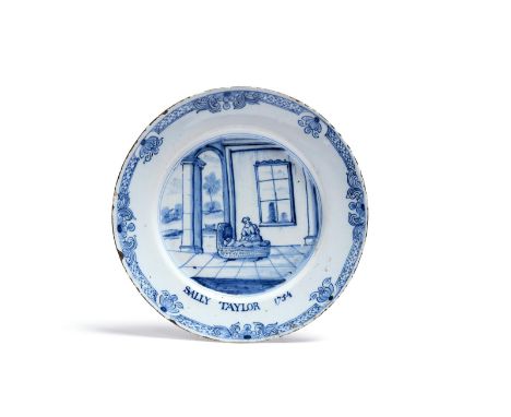 A documentary delftware plate  dated 1754, painted in blue with a mother tending a child in a large cot on a paved terrace be