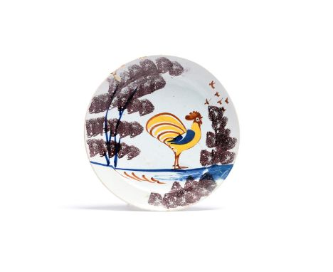 A Bristol delftware 'Farmyard' plate  c.1720-30, painted with a bold cockerel in yellow, blue and red, standing between spong