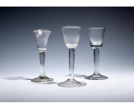 A gin glass and two small wine glasses  c.1730-40, the gin with a bell bowl over a folded foot, the wines with round funnel a