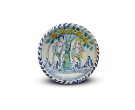 A Brislington delftware blue dash Adam and Eve charger  c.1700, painted with a scene of the Temptation, the couple standing e