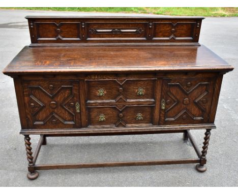 A 1920s Jacobean style oak dresser, with raised back above two central doors flanked by cupboard doors on turned and block le