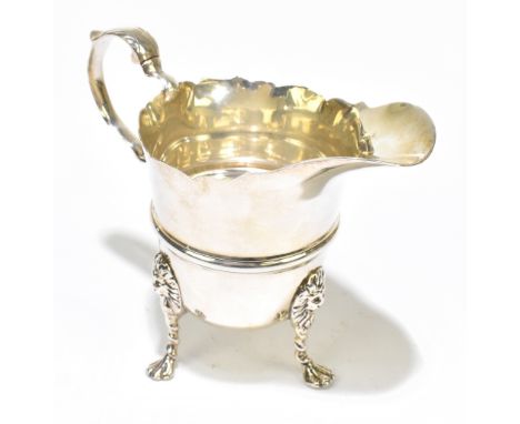 WEST &amp; SONS; an Irish Edwardian hallmarked silver cream jug in the 18th century manner, raised on three lion head capped 