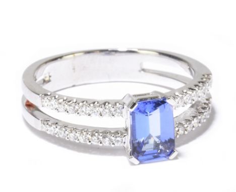 An 18ct white gold tanzanite and diamond ring, the central emerald cut tanzanite set with thirty-two tiny diamonds to the pie