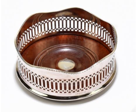 An Elizabeth II hallmarked silver bottle coaster with pierced shaped rim and central circular plaque to the wooden base, Shef