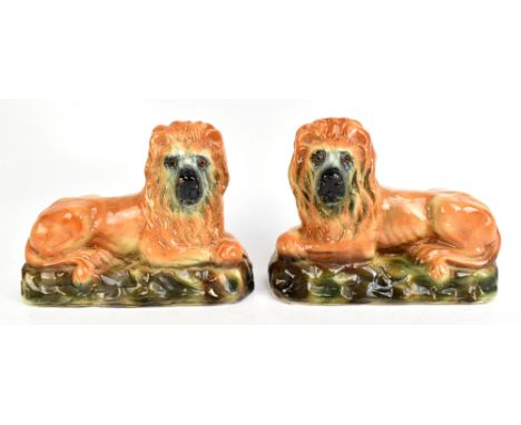 A pair of late 19th century Staffordshire lions, with glass eyes, raised on naturalistic oval plinth base, length 31cm (2).Ad