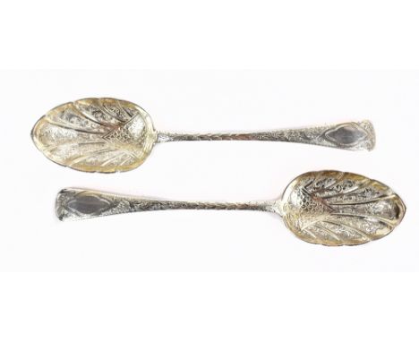 A pair of Victorian hallmarked silver serving spoons with cast detail to the shell shaped bowls, the handles with scrolling d