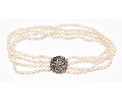 A four strand pearl choker necklace with diamond set white metal clasp, the foliate pierced white metal circular clasp set wi