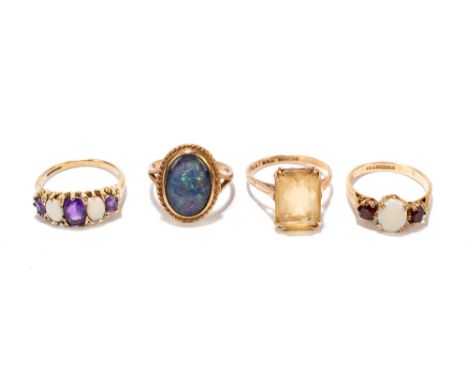 Four 9ct yellow gold dress rings including a three stone example set with an oval cabochon, size M1/2, a black opal example, 