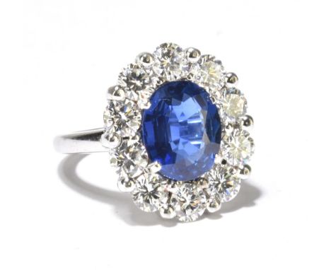 An 18ct white gold diamond and sapphire cluster ring, the central oval cut sapphire weighing approx 3.5ct, surrounded by ten 