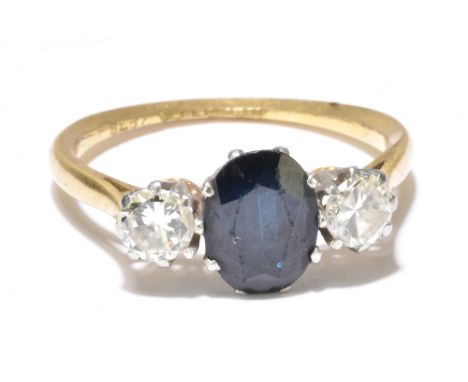 An 18ct yellow gold platinum mounted sapphire and diamond three stone ring, the central oval sapphire flanked by twin diamond