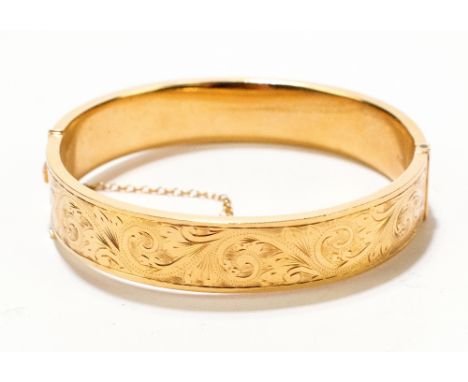 An 18ct yellow gold hinged snap bangle with chased foliate scroll detail, diameter 6.5cm, approx 26.9g.Additional Information