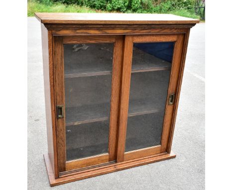 An Edwardian oak bookcase, with two glazed doors enclosing adjustable shelf, on plinth base, height 107cm, width 99cm, depth 