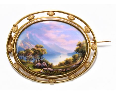 A Swiss yellow metal and enamelled oval brooch with pierced frame and central landscape inscribed to the reverse 'Le Soir, au