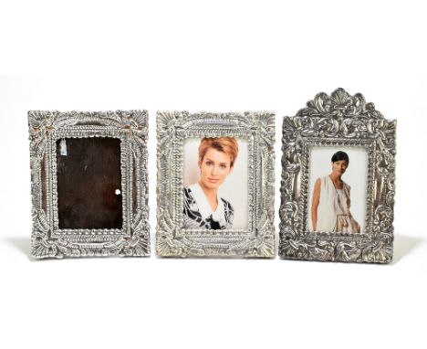 Three sterling silver mounted easel back photograph frames comprising a single example with cast floral detail surrounding a 