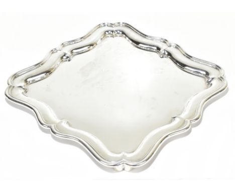 MARTIN HALL &amp; CO LTD; a George V hallmarked silver tray of shaped square section, raised on scrolling corner supports, Sh