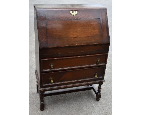 An early 20th century oak bureau, the fall front enclosing five pigeon holes above a secret drawer and two further drawers, r