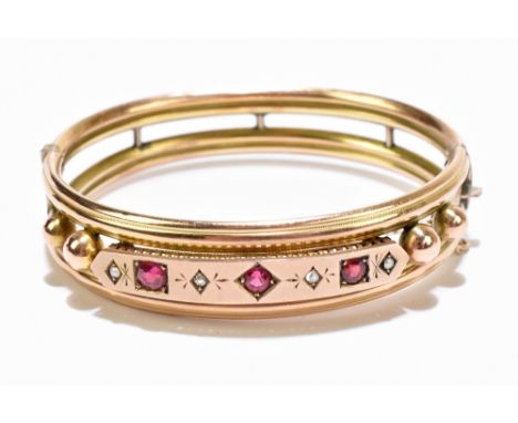 A Victorian yellow metal snap bangle, set with seed pearls, with three ruby coloured stone and two clear stones, unmarked, ap