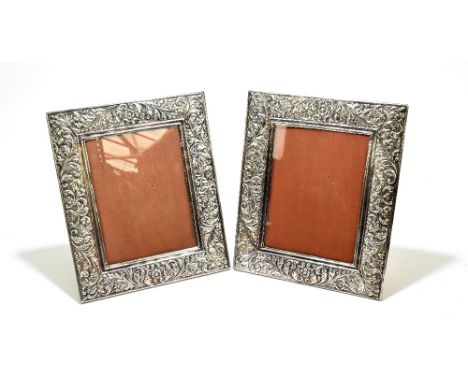 A pair of sterling silver easel back photograph frames of rectangular form, with cast scrolling detail, each stamped 925, 33 