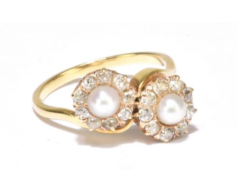 A yellow metal diamond and pearl crossover ring fashioned from two ear studs, each circular platform centered with a cut cult