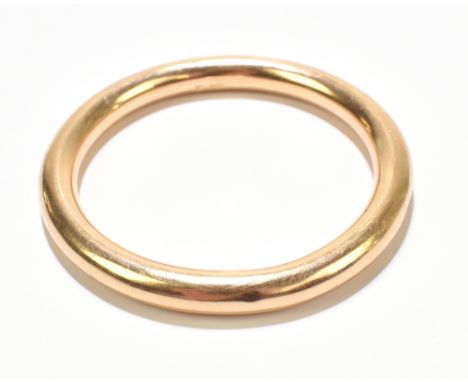 A yellow metal solid hollow bangle indistinctly stamped possibly 15c, external width 8.5cm, internal width 7.5cm, approx 24g.