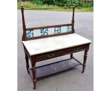 A late Victorian pitch pine marble top wash stand, the raised back inset with seven floral ceramic tiles, above two drawers a