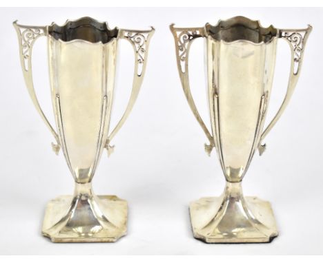 ROBERTS &amp; BELK; a pair of George V hallmarked silver vases of shaped outline with pierced scroll handles on spread shaped