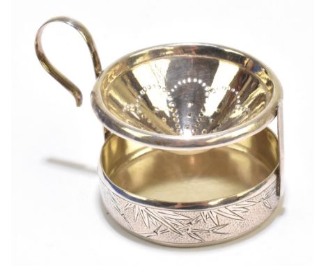 An early 20th century Chinese silver tea strainer on stand, the stand with bright cut bamboo decoration against textured grou
