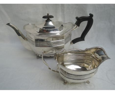 A matched silver tea pot and cream jug having gadrooned decoration to shaped rims, lion mask bracket feet and reeded decorati