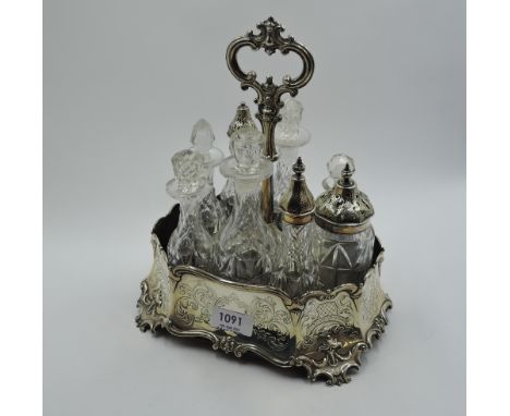 A Victorian silver condiment stand having engraved decoration, moulded rim and bracket feet, containing eight cut crystal bot