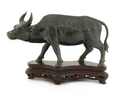 A Chinese jade buffalo,late Qing dynasty, standing with its head slightly turned to the left, the stone of spinach tone with 