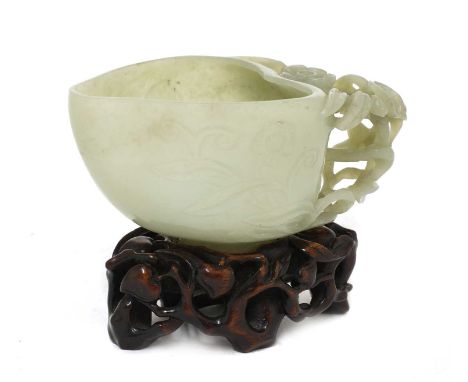 A Chinese jade cup,Ming dynasty (1368-1644), in the shape of a peach on a prunus-shaped foot, the side carved with foliage, a