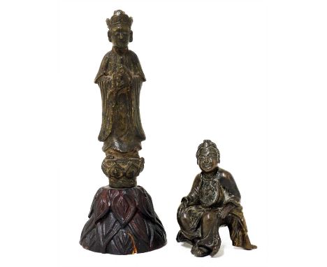 A Chinese bronze figure, seated wearing a long robe tied around the waist, his legs relaxed at ease, both hands resting on hi