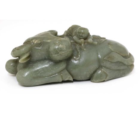 A Chinese jade carving,late Qing dynasty, of a large recumbent buffalo with a boy lying on its back, the stone of celadon ton