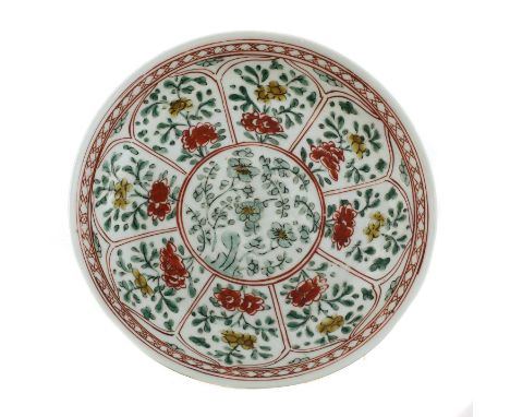 A Chinese wucai plate,Kangxi (1662-1722), of circular form, the centre painted with blossoming prunus by a rock, surrounded b