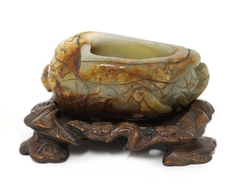 A Chinese jade brush washer, Qing dynasty (1644-1911), carved in relief with lotus flowers and leaves, the stone with russet 