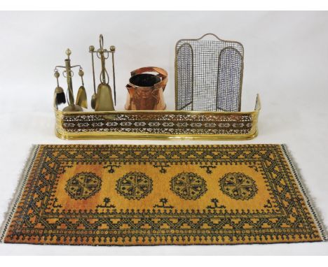 A 19th century brass fender, a 19th century copper jug, fire screen and brass fire tools, and a Turkish rug