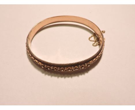 A 9ct gold hinged bangle, Birmingham 1902, with Etruscan style decoration to the top half