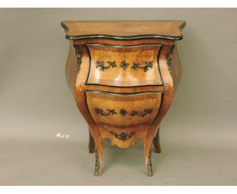 An early 20th century Continental walnut bombe two drawer commode, the drawers and top with ebonised border and metal mounts,