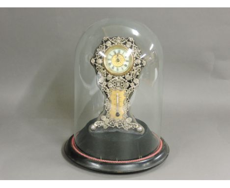 A pierced desk clock and thermometer, fixed to a black velvet stand, under a glass dome, cracked, 27cm high