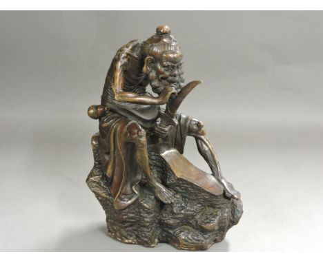 A Chinese bronze figure holding his sword to his beard, signed, 29.5cm high