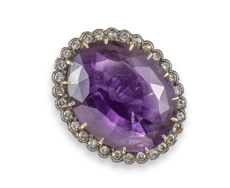 A large amethyst and diamond ring, the oval-shaped amethyst is set within a surround of circular-cut diamonds in silver and g