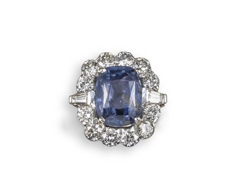 A sapphire and diamond cluster ring, the cushion-shaped sapphire set within a surround of twelve round brilliant-cut diamonds