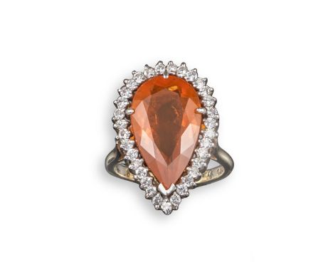 A fire opal and diamond cluster ring, the pear-shaped fire opal is set within a surround of small circular-cut diamonds in pl