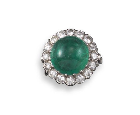 An emerald and diamond cluster ring, the circular emerald cabochon is set within a surround of circular-cut diamonds in plati