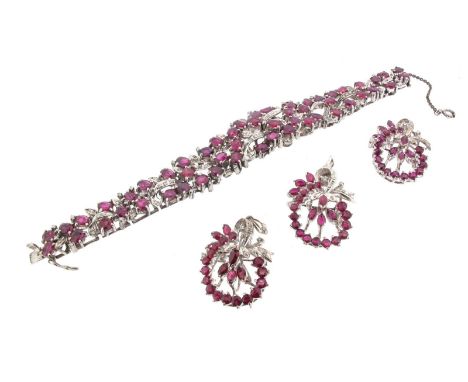A ruby and diamond scroll bracelet, set overall with graduated oval-shaped rubies and diamond-set scrolls in white gold, with