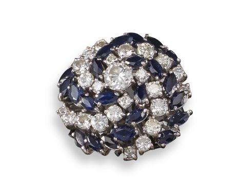 A sapphire and diamond cluster ring, set with concentric swirls of marquise-shaped sapphires and round brilliant-cut diamonds