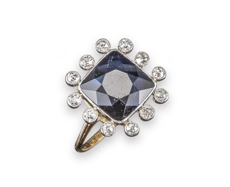 A sapphire and diamond cluster ring, the square-cut sapphire is millegrain-set within a border of old circular-cut diamonds i