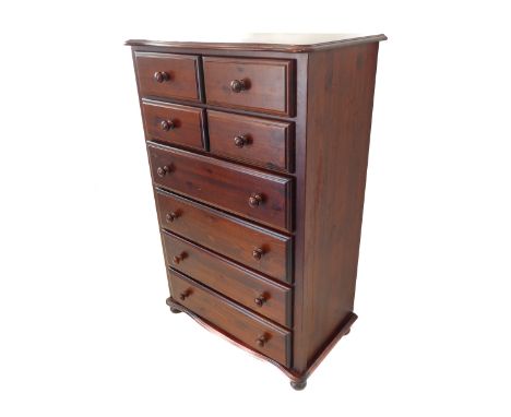 A modern stained pine chest: the serpentine moulded top above an arrangement of four half-width over four full-width drawers,