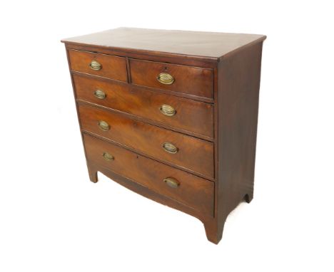 A 19th century mahogany chest: two half-width and three full-width graduated drawers with stamped brass ovals, shaped apron a