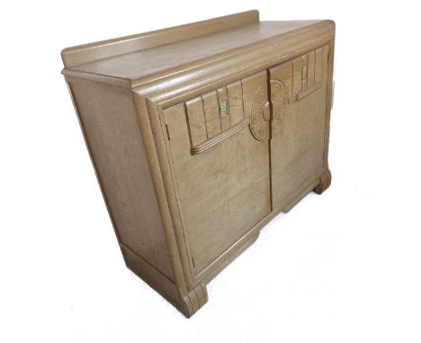 An Art Deco period bleached oak side cabinet: two doors opening to reveal shelf space and two inner drawers, raised on shaped